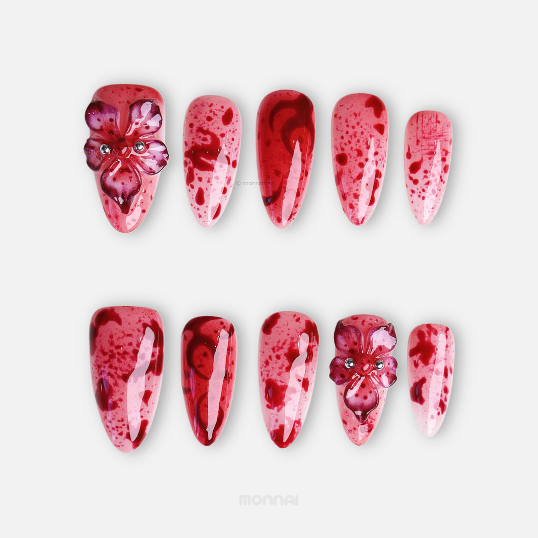 999 Roses press-on nails laid out in close-up, pink and red splatter design with 3D gothic flowers and glossy finish.