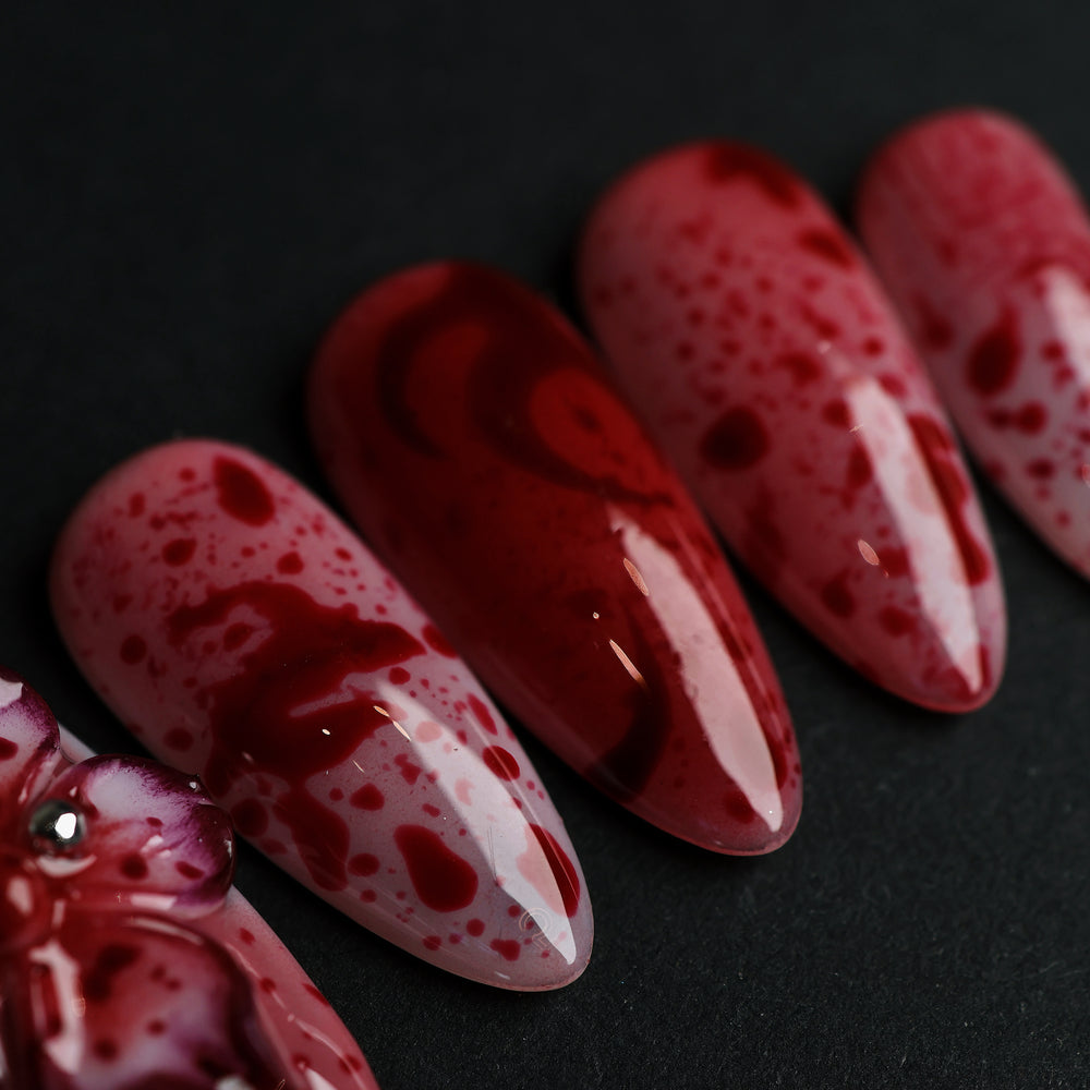 999 Roses press-on nails in close-up, soft pink with red splatter and high-gloss gothic floral detail