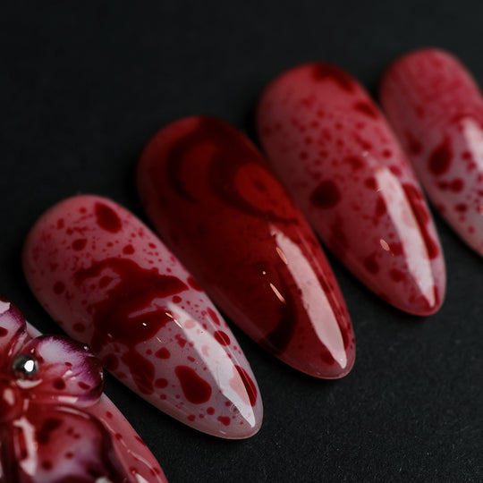 999 Roses press-on nails in close-up, soft pink with red splatter and high-gloss gothic floral detail