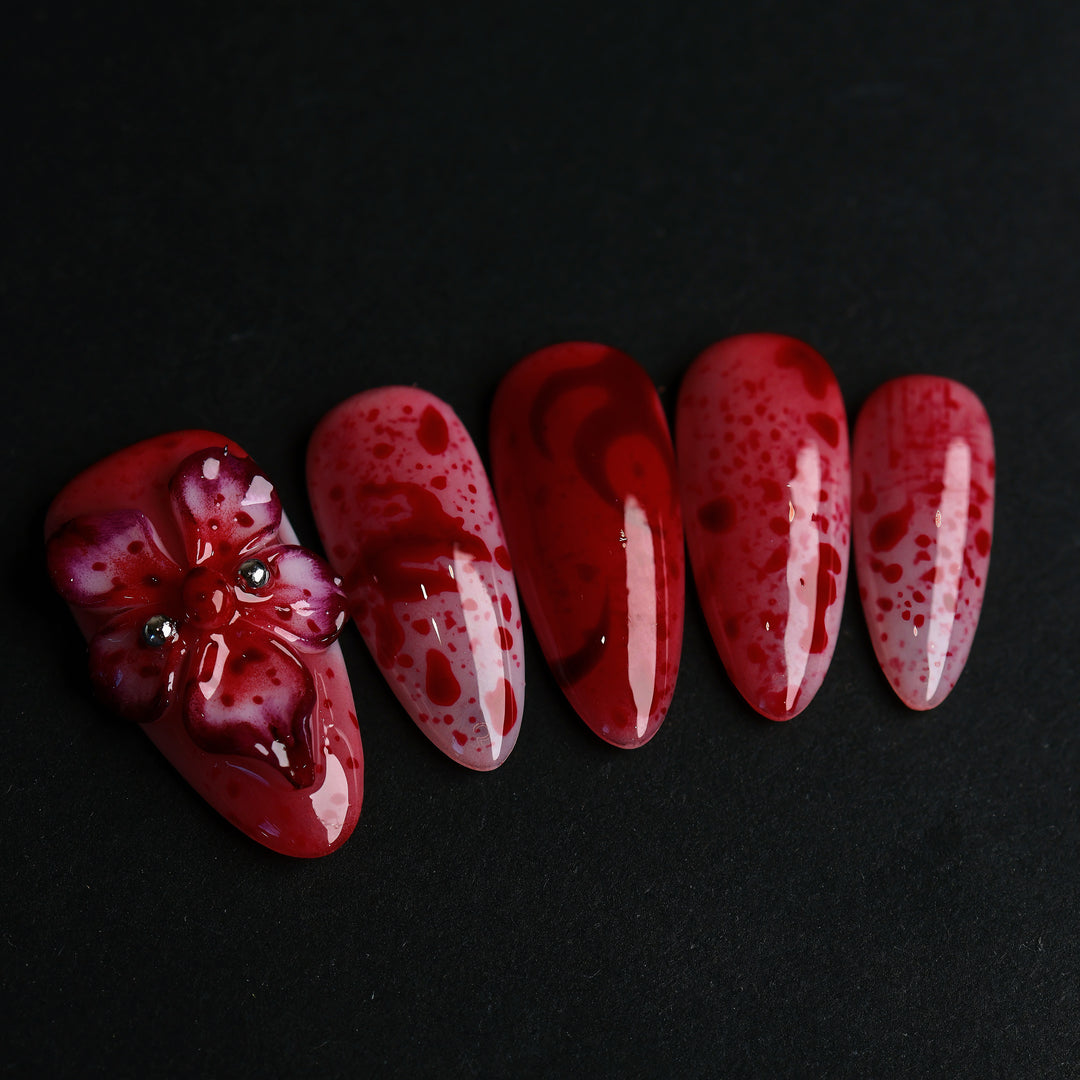 999 Roses press-on nails in close-up, red splatter on soft pink with a gothic 3D flower and glossy finish.