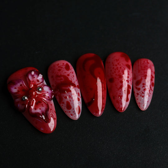 999 Roses press-on nails in close-up, red splatter on soft pink with a gothic 3D flower and glossy finish.
