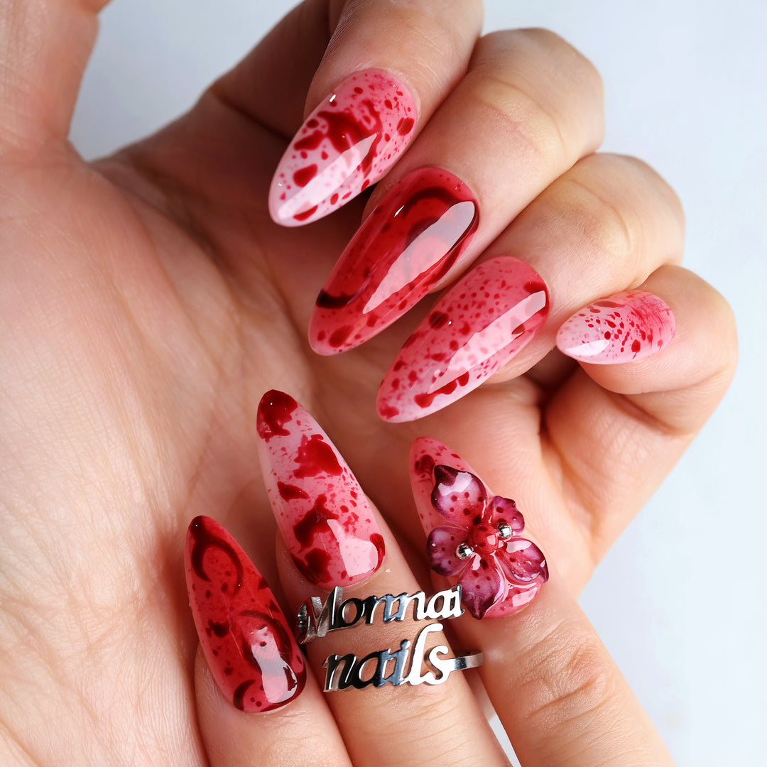 999 Roses press-on nails worn on hand, red splatter over soft pink with glossy finish and 3D gothic flower accent