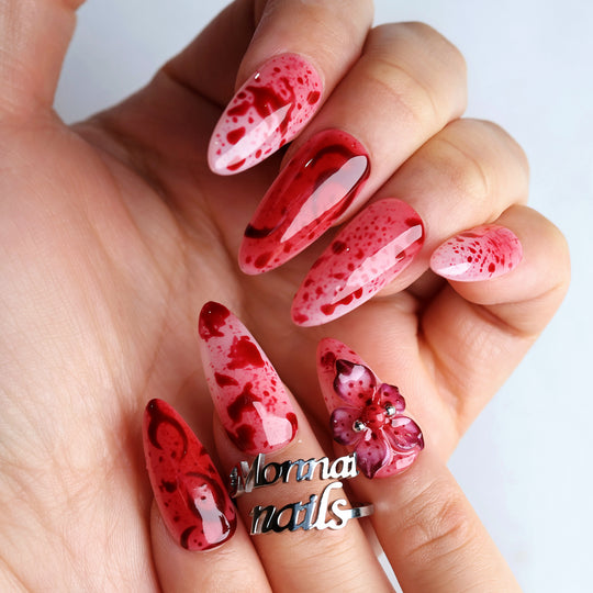 999 Roses press-on nails worn on hand, red splatter over soft pink with glossy finish and 3D gothic flower accent
