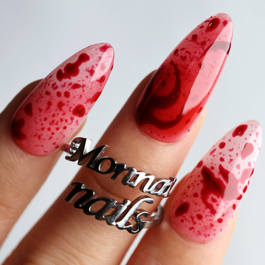 999 Roses press-on nails worn on hand, red splatter over pink with glossy finish