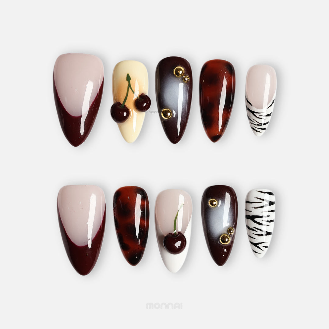 A Little Sweet press-on nails with glossy cherry accents, tortoiseshell, zebra stripes and French tips on a nude base.