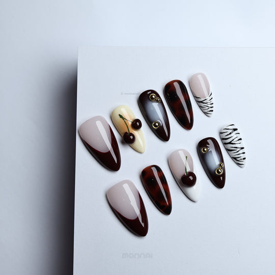 A Little Sweet press-on nails laid out with vintage edge, glossy cherry accents, tortoiseshell, zebra stripes, and nude bases.