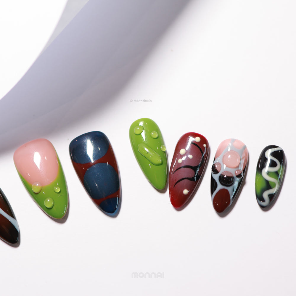 Abstract Flow press-on nails laid out, showing funky abstract designs with vibrant color blocks and 3D dewdrop accents.