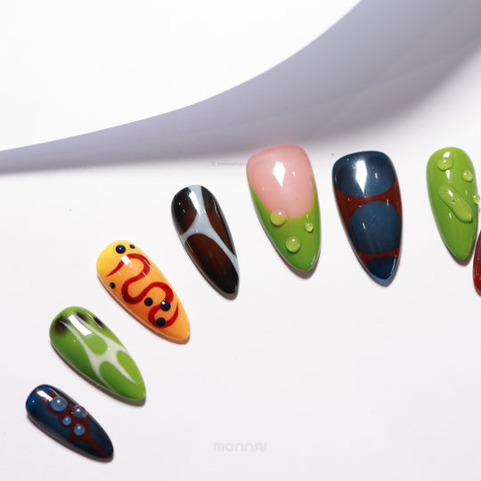 Abstract Flow press-on nails laid out in vibrant abstract shapes with wavy lines, color blocks, and clear dewdrop accents.