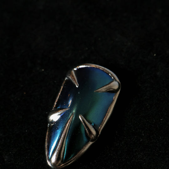 Alien press-on nails in close-up, featuring a blue-green chrome base with sculpted silver spikes and metallic edges.