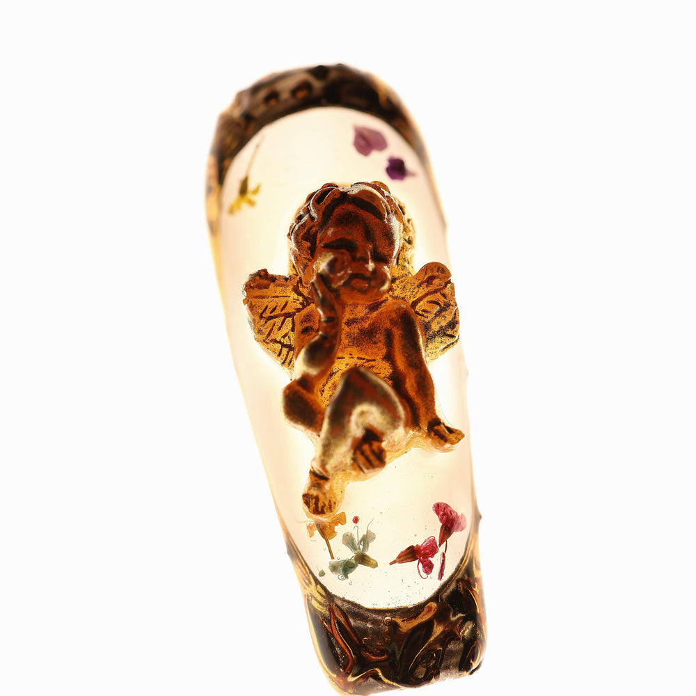 Angel Glow press-on nails in close-up, with milky base, dried botanical flowers, and a 3D gold cherub charm in Renaissance style.