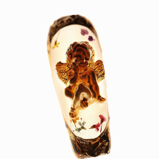 Angel Glow press-on nails in close-up, with milky base, dried botanical flowers, and a 3D gold cherub charm in Renaissance style.