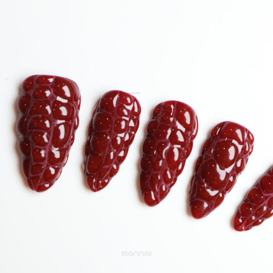Antique Elegance press-on nails in rich dark red crocodile texture with a glossy finish, laid out in close-up.