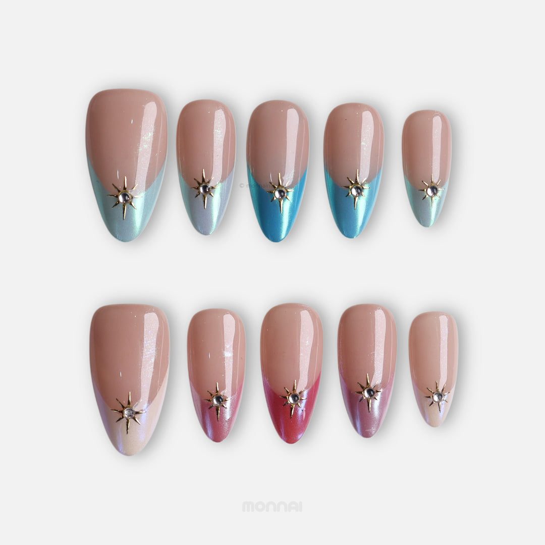 Aurora Gleam press-on nails shown laid out, nude with pearlized blue and pink French tips and gold starburst charms