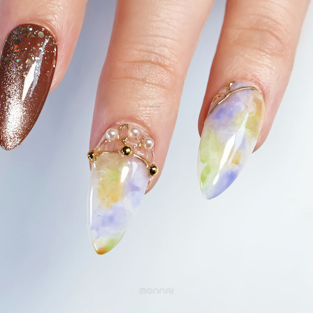 Aurora Veil press-on nails worn on hand, with green and lavender watercolor blending, gold lines, pearl accents, and brown shimmer.