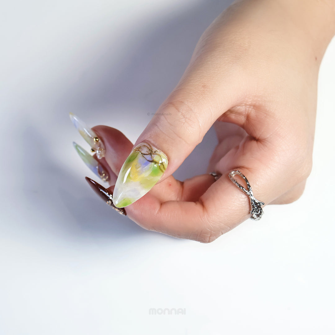 Aurora Veil press-on nails worn on hand, with green and lavender watercolor blending, gold lines and pearl accents
