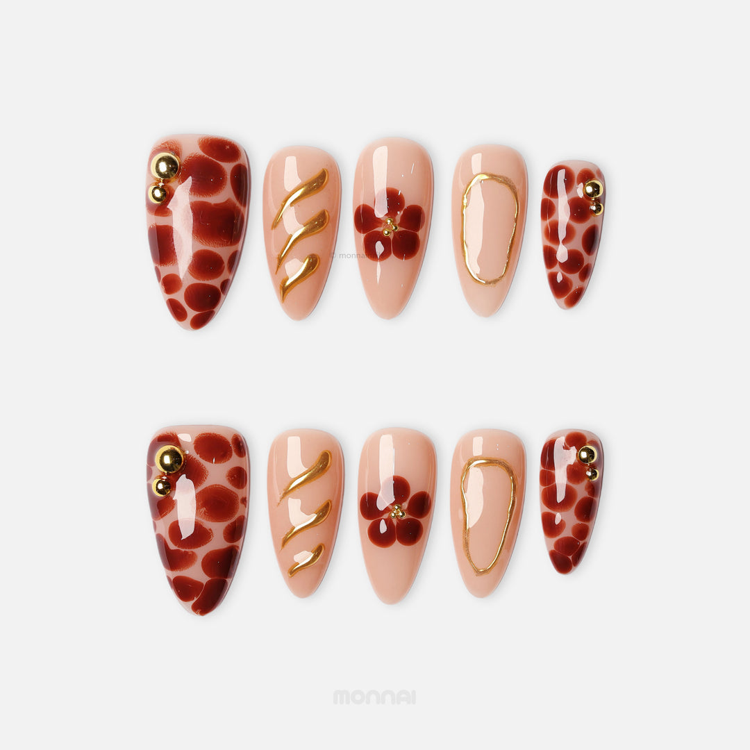 Autumn Touch press-on nails with sheer nude base, red florals, spotted accents and gold lines laid out in two rows