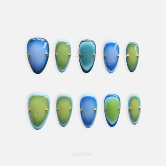 Azure Olive press-on nails laid out in blue and green gradient with gold studs and glossy finish