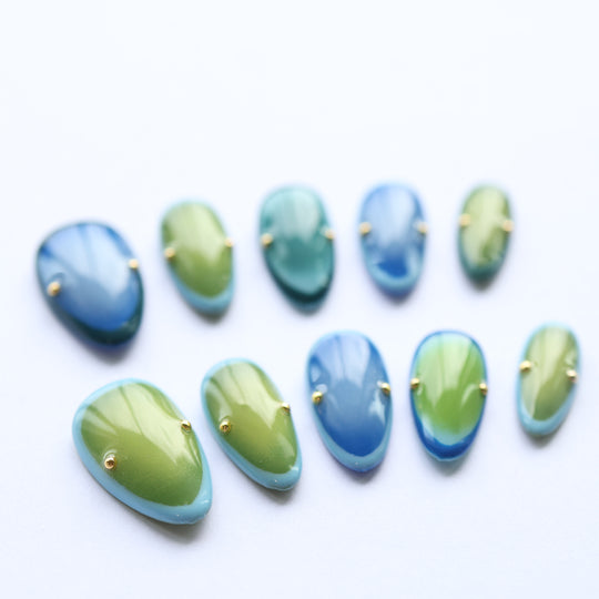 Azure Olive press-on nails laid out with blue-green gradient and gold studs on a white background