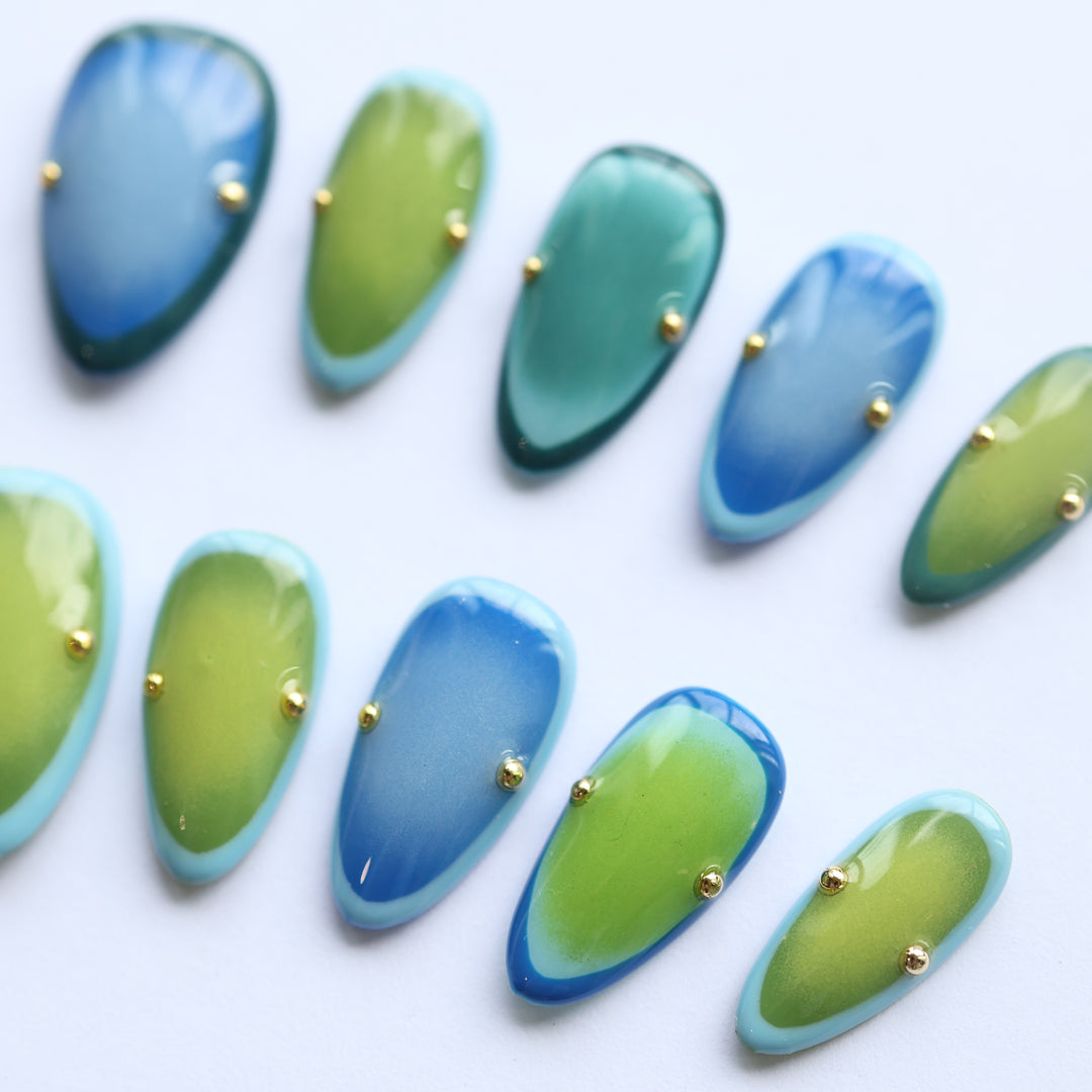Azure Olive press-on nails laid out in blue and green aura gradients with gold studs