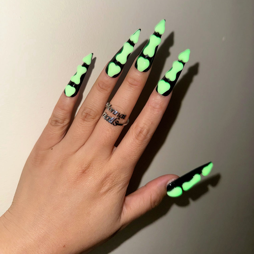 Bad to the Bone press-on nails worn on hand, black gothic nails with glowing green bone segments
