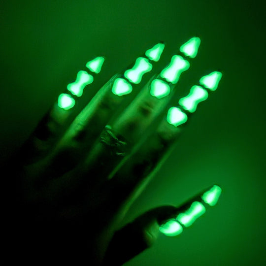 Bad to the Bone gothic press-on nails shown on hand, glowing green bone segments over deep obsidian base