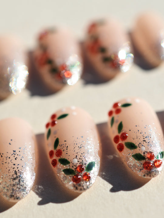 Berry Frost Christmas-themed press-on nails close-up with nude base, silver glitter gradient, red berries and green leaves.