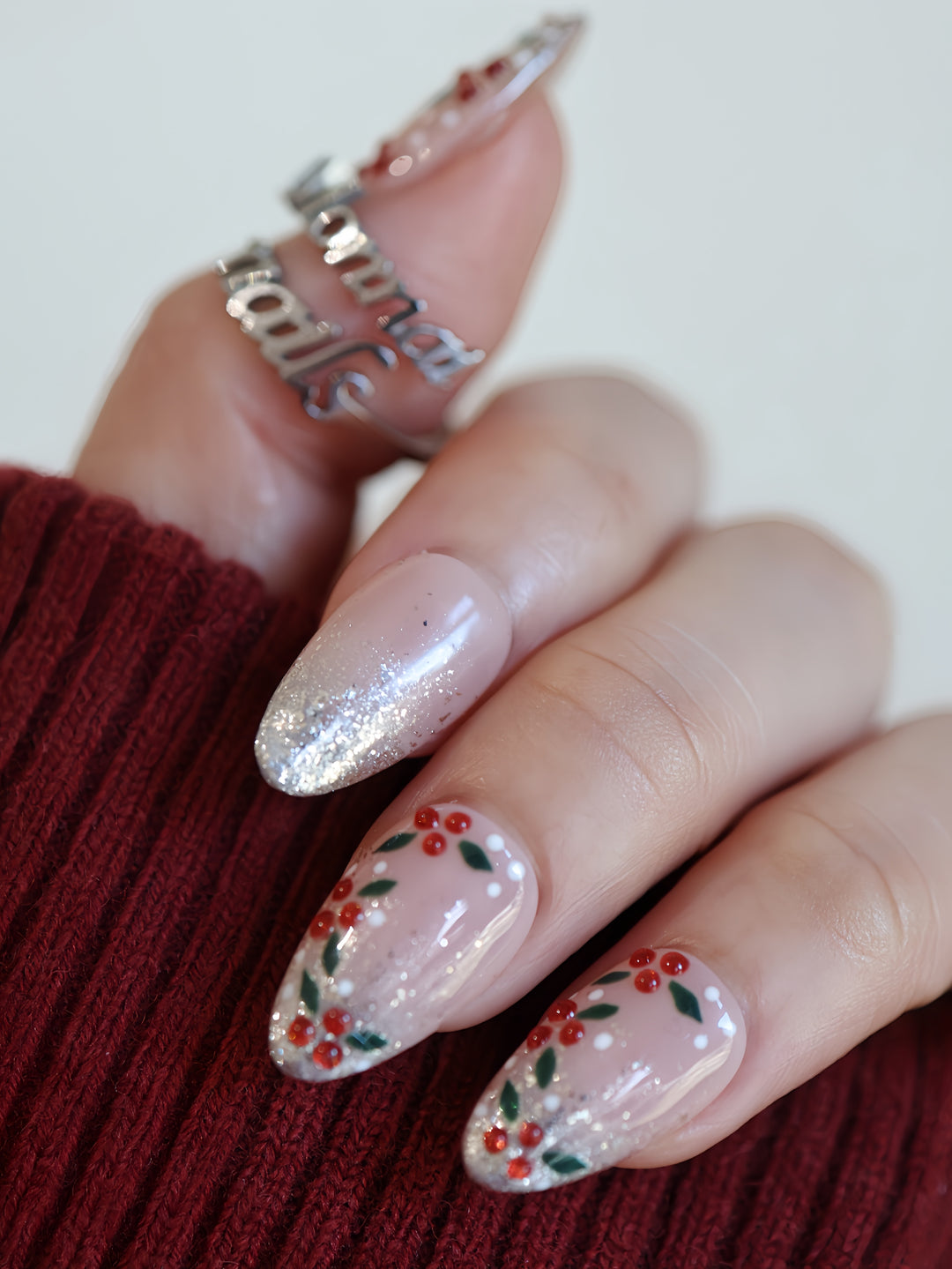 Berry Frost Christmas-themed press-on nails on hand, with silver glitter tips and berry vine nail art.