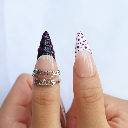 Berry Spin press-on nails worn on hands, with sheer nude bases, purple polka dots, and black French tip accents.