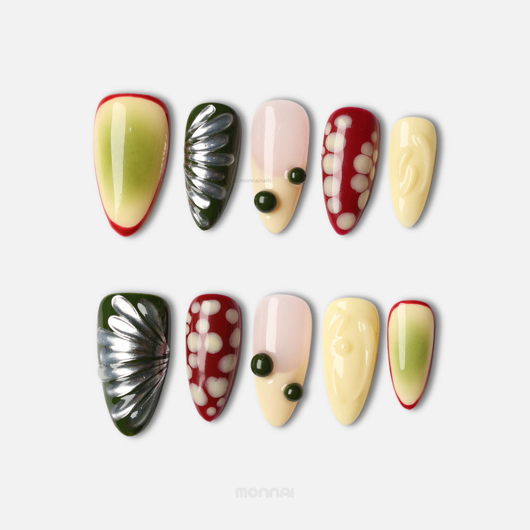 Berry press-on nails laid out in mixed playful design, with glossy cream, red, green and dotted abstract shapes