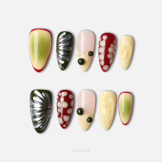 Berry press-on nails laid out in mixed playful design, with glossy cream, red, green and dotted abstract shapes