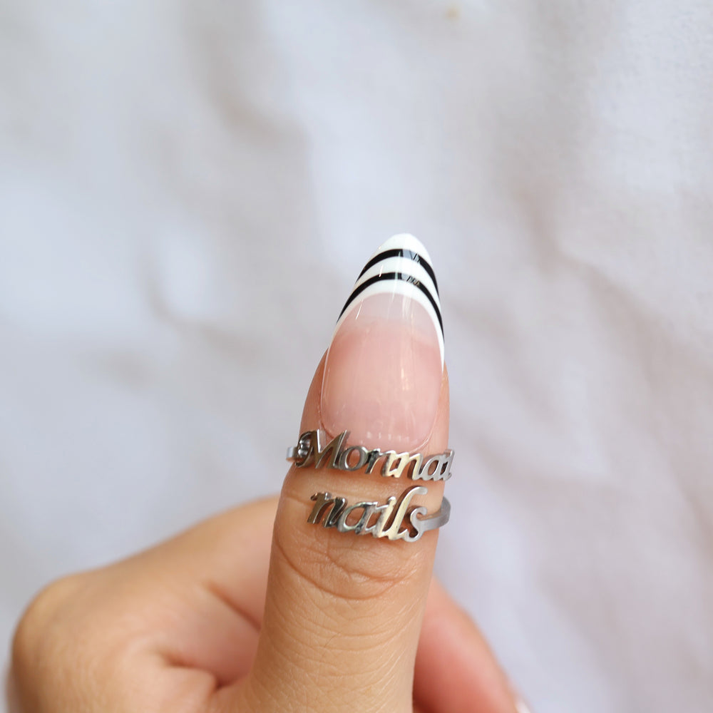 Black & White press-on nails on a thumb, close-up with nude pink base and black white striped French tip.
