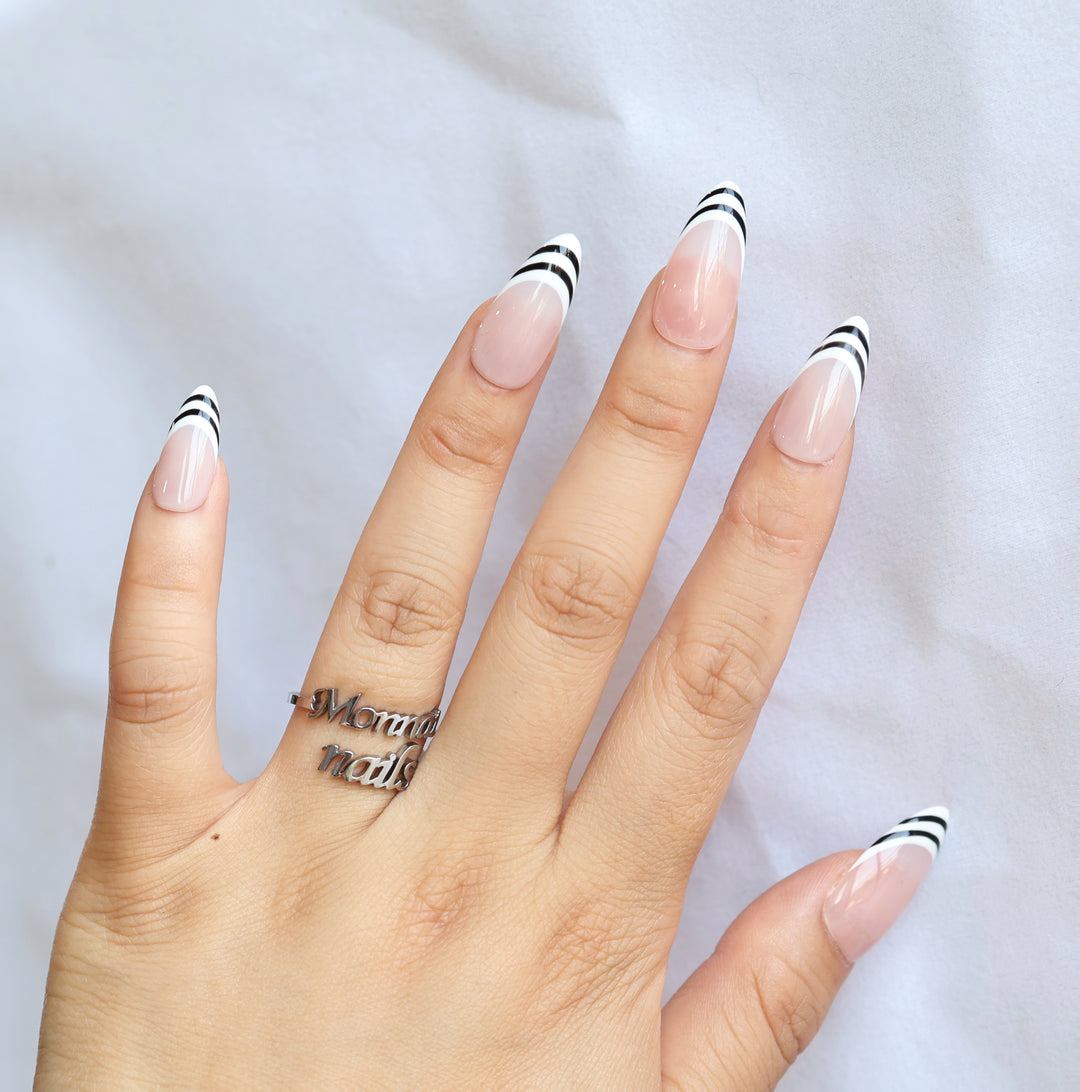 Black &amp; White press-on nails worn on hand, nude pink base with black and white striped French tips, sleek gel-gloss finish.