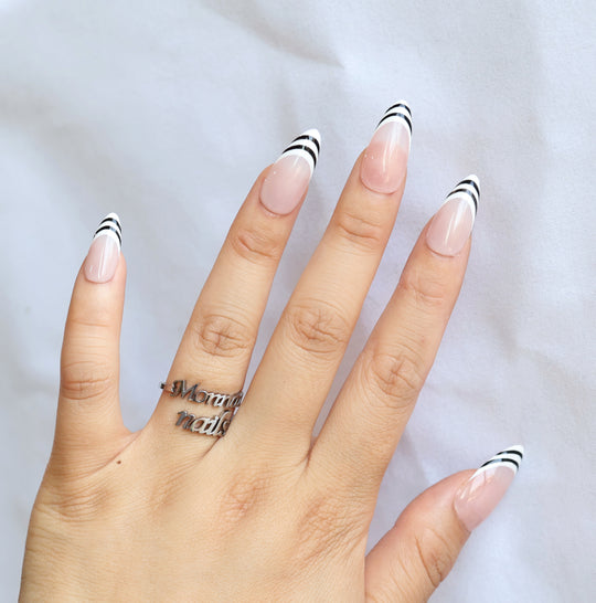 Black &amp; White press-on nails worn on hand, nude pink base with black and white striped French tips, sleek gel-gloss finish.