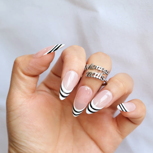 Black &amp; White press-on nails worn on hand, showing nude pink base with black and white striped French tips.