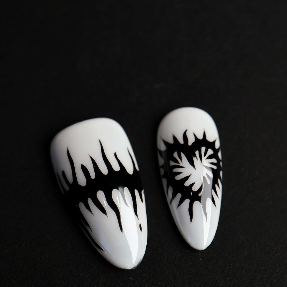 Black or White press-on nails with black melting spikes and a heart motif, shown in close-up.