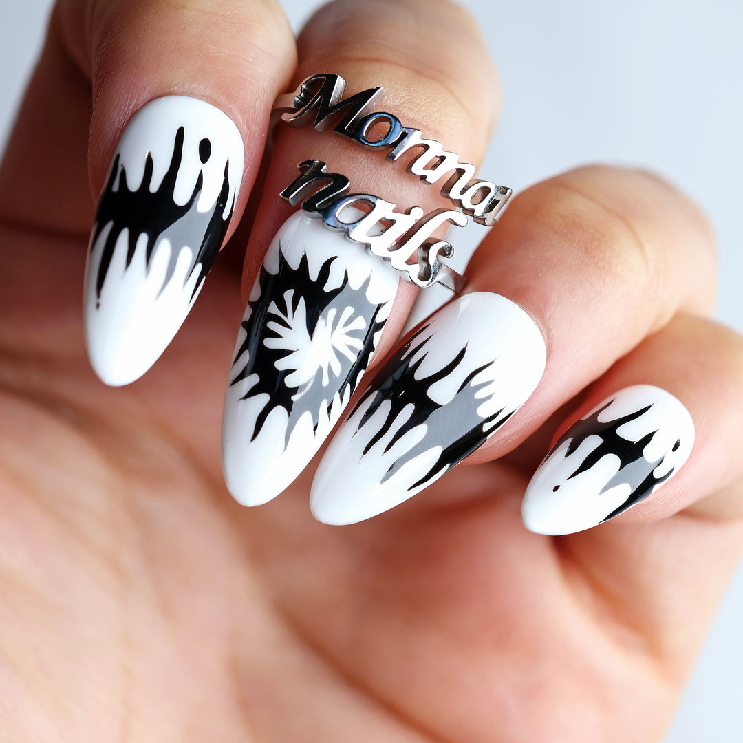 Black or White press-on nails worn on hand, bold black melting spikes over white with dark romantic heart motifs.