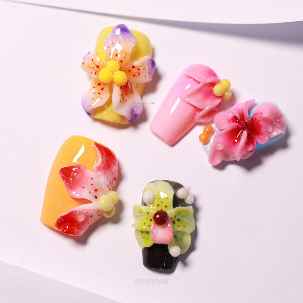 Blooming Paradise press-on nails laid out in colorful close-up with 3D floral details, dewdrop accents, and glossy gel finish