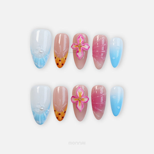 Blossom Breeze press-on nails laid out with blue and orange French tips, pink flower, pearls, and glossy tropical ripples