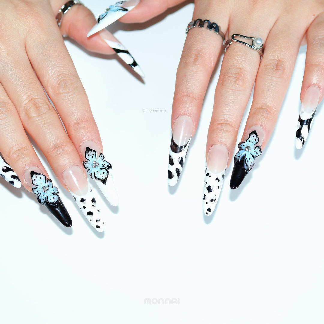 Blue Bloom press-on nails on hands, with black-and-white zebra print, nude base, and blue 3D flowers
