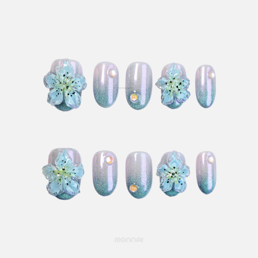 Blue Ice press-on nails with icy shimmer, gradient cat-eye base, and translucent blue 3D flowers laid out in a set