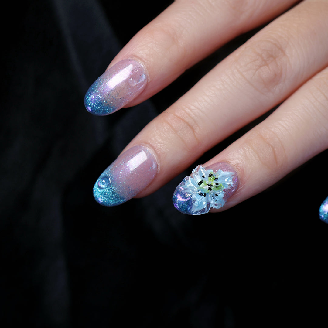Blue Ice press-on nails worn on hand with icy glow, translucent blue 3D flower, and fine shimmer