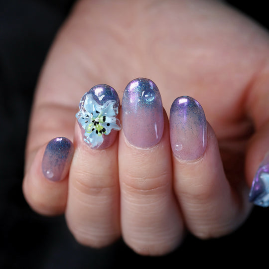 Blue Ice press-on nails on hand, icy glow with soft florals, gradient cat-eye shimmer and translucent blue 3D flower accent