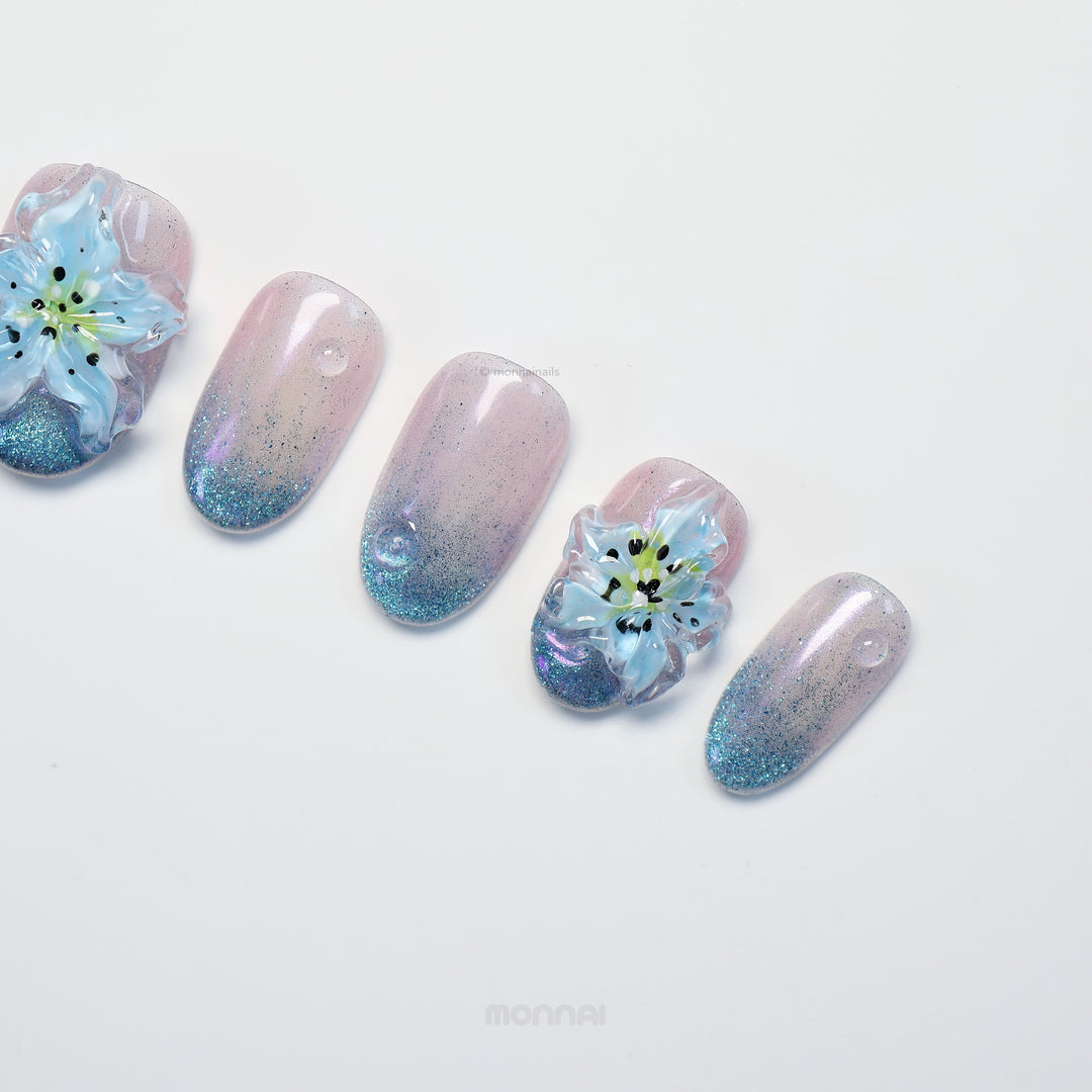 Blue Ice press-on nails laid out with icy gradient cat-eye shimmer and translucent blue 3D flowers