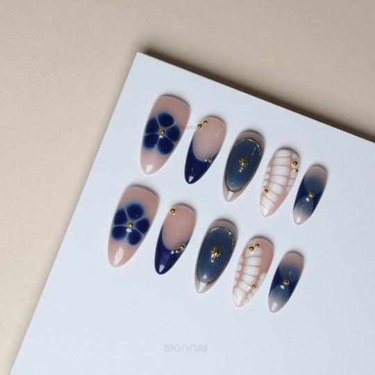 Blue Jasmine press-on nails laid out with navy tips, blue florals, white crocodile pattern and gold star charms