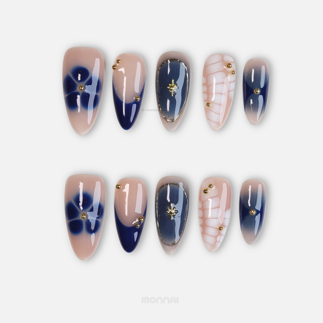 Blue Jasmine press-on nails laid out with jelly nude bases, navy blue tips, white crocodile pattern, and gold star charms.