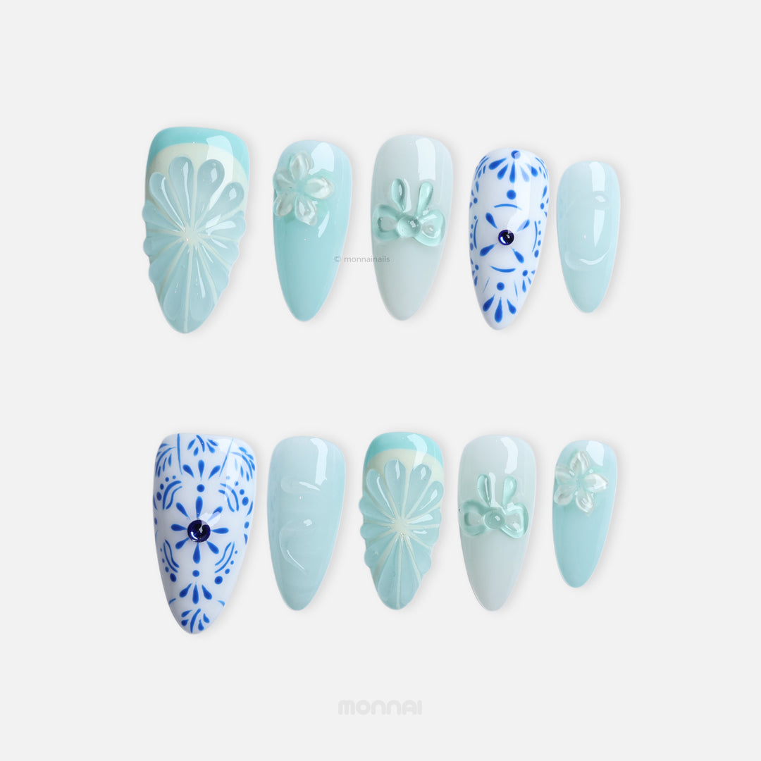 Blue Porcelain press-on nails with pale blue boho-style floral and citrus-inspired 3D accents, shown in close-up.