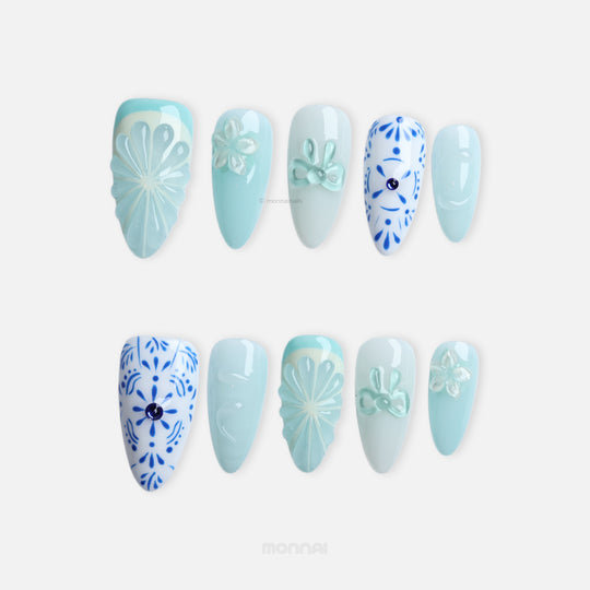 Blue Porcelain press-on nails with pale blue boho-style floral and citrus-inspired 3D accents, shown in close-up.