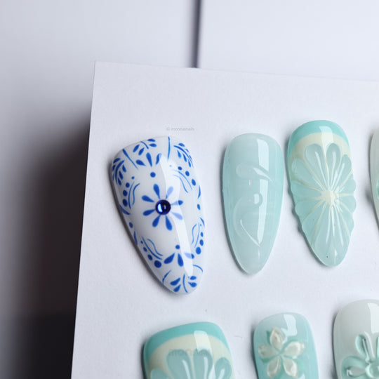 Blue Porcelain press-on nails with blue boho floral pattern and light citrus-inspired texture, shown laid out in close-up