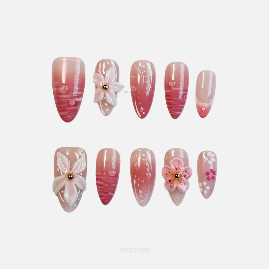 Blush Petals press-on nails shown in close-up with pale pink, sheer bases, white floral accents, hot pink swirls, and dewdrop details