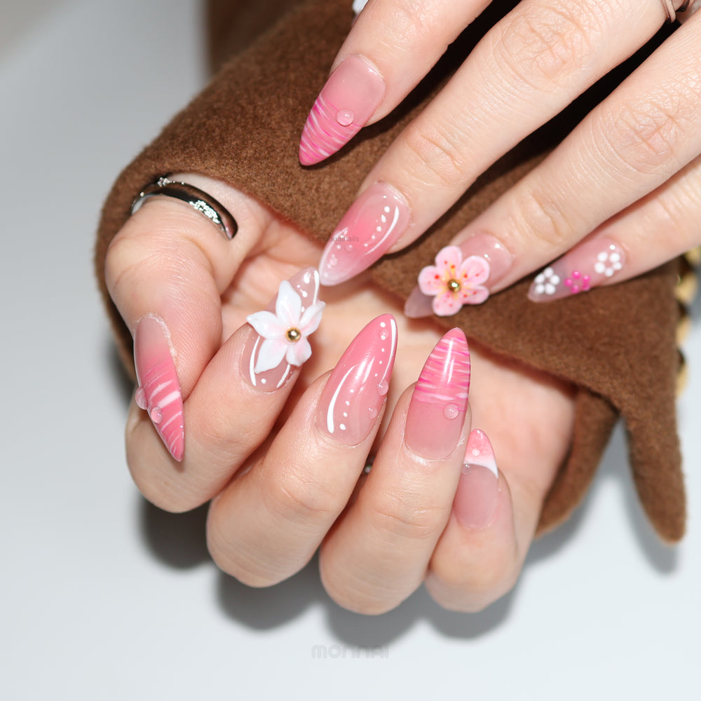 Blush Petals press-on nails on hands with pale pink bases, hot pink stripes, 3D white flowers, and gold centers